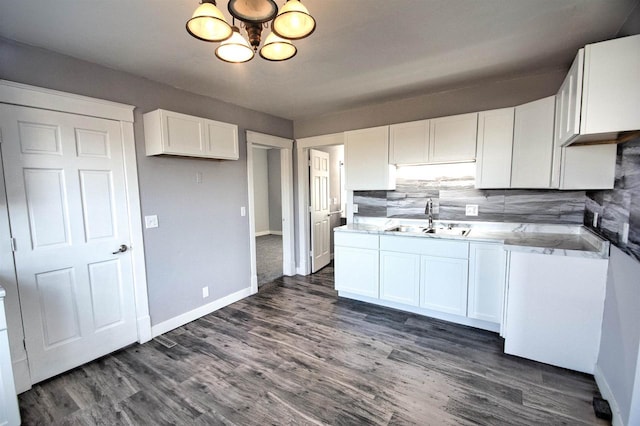 kitchen featuring tasteful backsplash, dark wood finished floors, a chandelier, white cabinets, and a sink