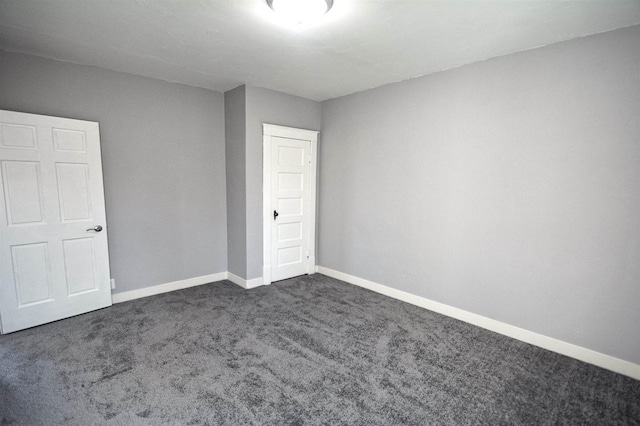 unfurnished bedroom with dark colored carpet, a closet, and baseboards