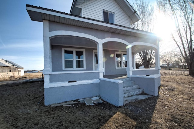 view of front of property featuring metal roof, a porch, and stucco siding