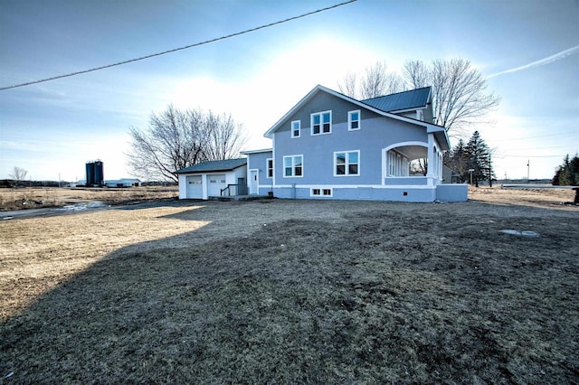 back of property featuring driveway, metal roof, and a garage