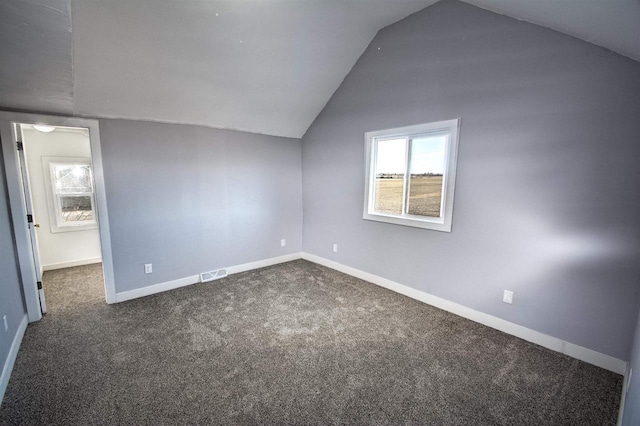 additional living space with visible vents, lofted ceiling, baseboards, and dark colored carpet