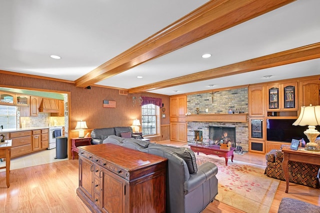 living area featuring visible vents, beamed ceiling, recessed lighting, light wood-style floors, and a brick fireplace