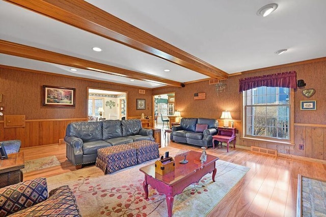 living room featuring beam ceiling, wood finished floors, and a healthy amount of sunlight