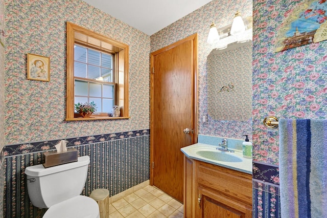 half bathroom with wallpapered walls, toilet, vanity, and tile patterned flooring