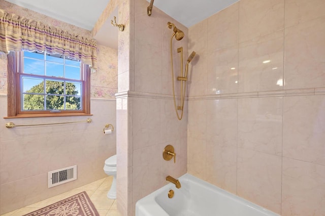 full bathroom with washtub / shower combination, visible vents, tile walls, toilet, and tile patterned floors