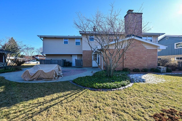 back of property with fence, a patio area, brick siding, and a lawn