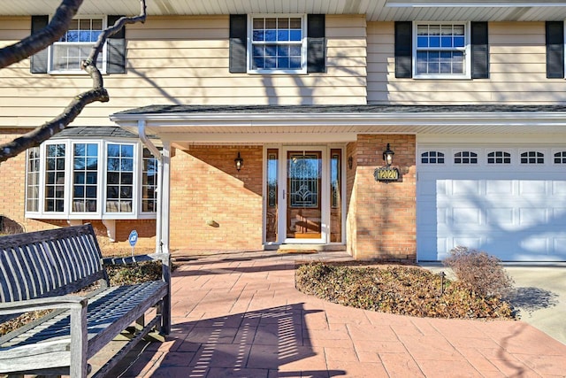 entrance to property featuring a garage and brick siding