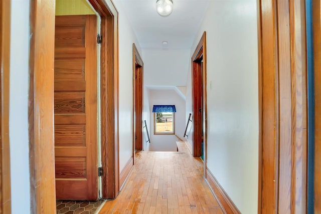 corridor with baseboards and hardwood / wood-style floors