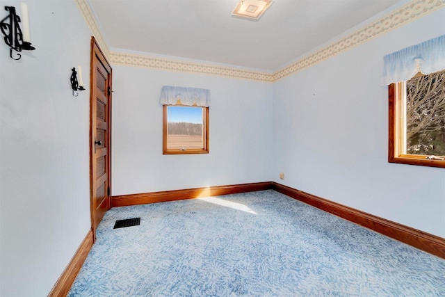 carpeted spare room with visible vents, baseboards, and ornamental molding