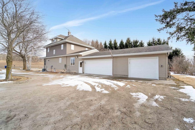 view of home's exterior featuring central AC unit, a garage, driveway, and a chimney