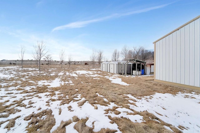 yard layered in snow with an outdoor structure and a shed