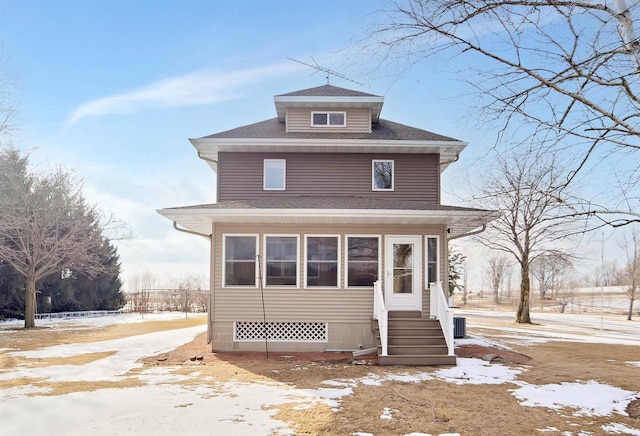 american foursquare style home with central air condition unit, roof with shingles, and entry steps