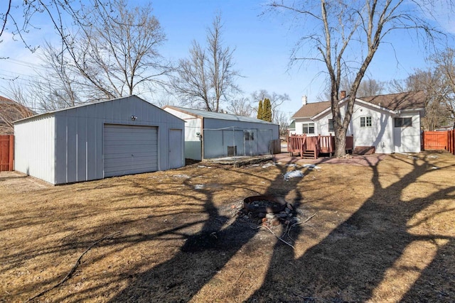 exterior space with fence, a deck, a garage, an outbuilding, and driveway