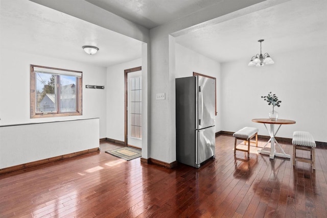 interior space featuring dark wood-type flooring, a notable chandelier, and baseboards