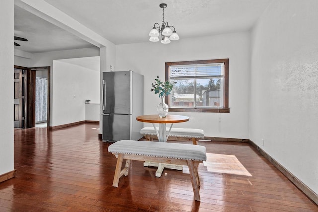 dining area featuring hardwood / wood-style floors, a notable chandelier, and baseboards