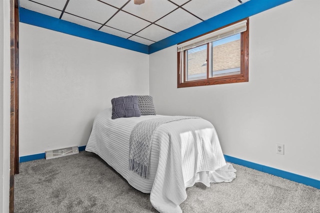 bedroom with a paneled ceiling, visible vents, carpet floors, and baseboards