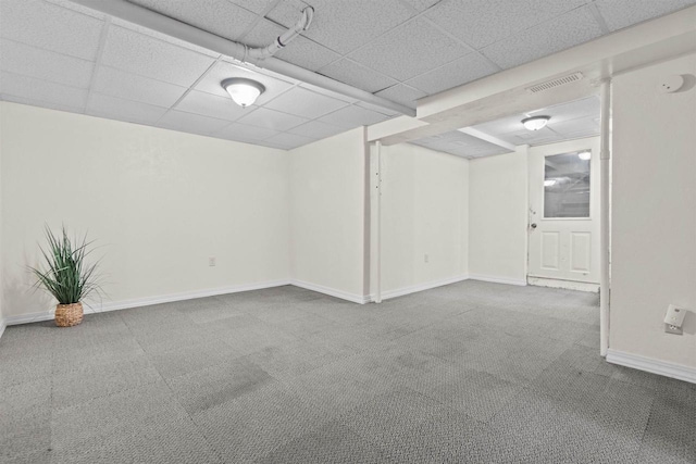 finished basement with carpet, visible vents, a drop ceiling, and baseboards