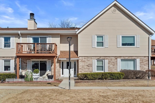 multi unit property featuring brick siding, a balcony, and a chimney