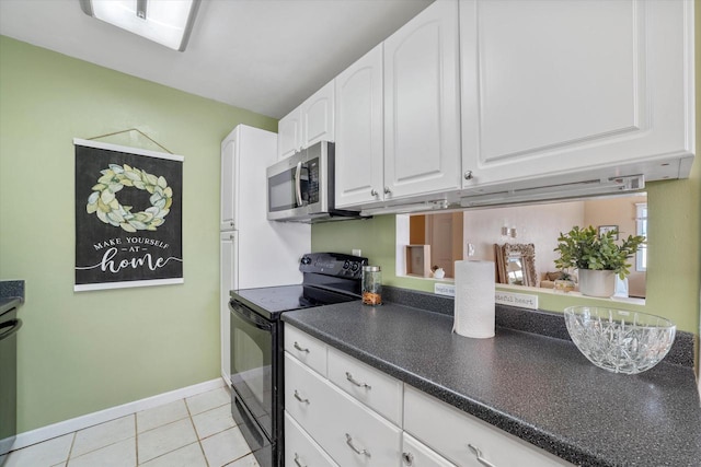 kitchen featuring dark countertops, stainless steel microwave, black range with electric cooktop, light tile patterned floors, and white cabinets