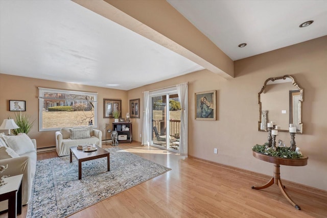 living area with beam ceiling, baseboard heating, baseboards, and wood finished floors