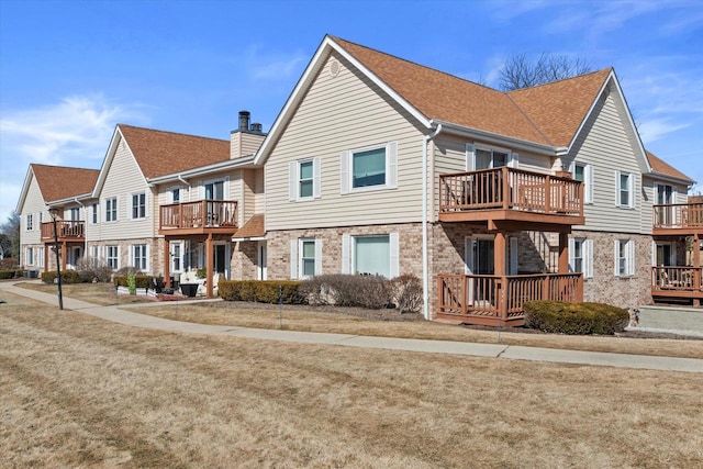 back of property featuring brick siding, a residential view, and roof with shingles