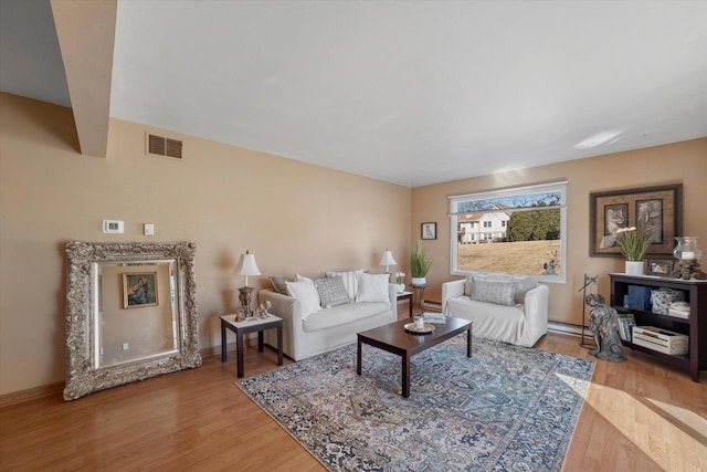 living area with visible vents, light wood-style flooring, baseboards, and a baseboard radiator