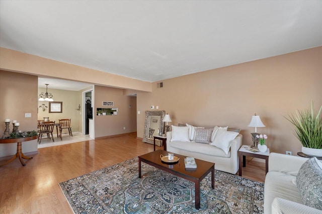 living area featuring a notable chandelier, visible vents, light wood-type flooring, and baseboards