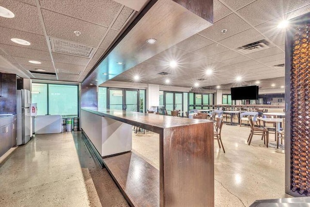 kitchen featuring visible vents, freestanding refrigerator, and a drop ceiling