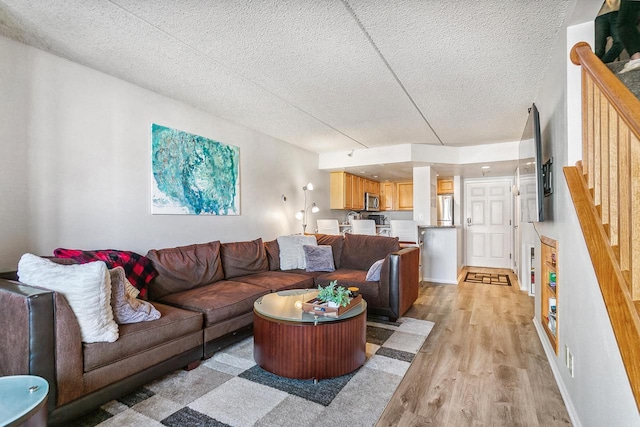 living room featuring light wood finished floors, a textured ceiling, and baseboards