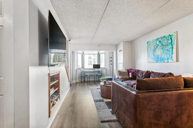 living area with a textured ceiling, baseboards, and wood finished floors