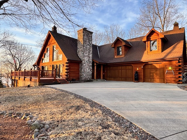 log-style house featuring log siding, driveway, and a chimney