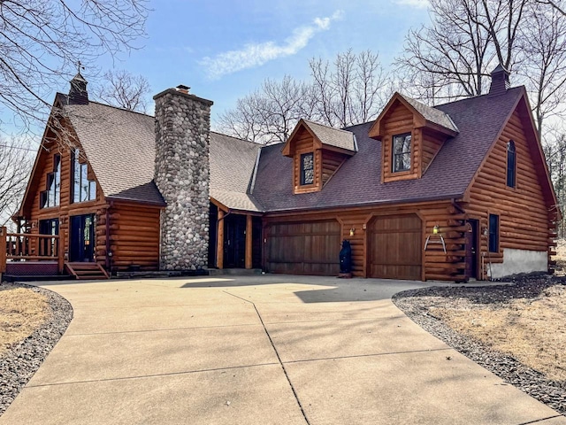 cabin with concrete driveway, log siding, roof with shingles, and a chimney