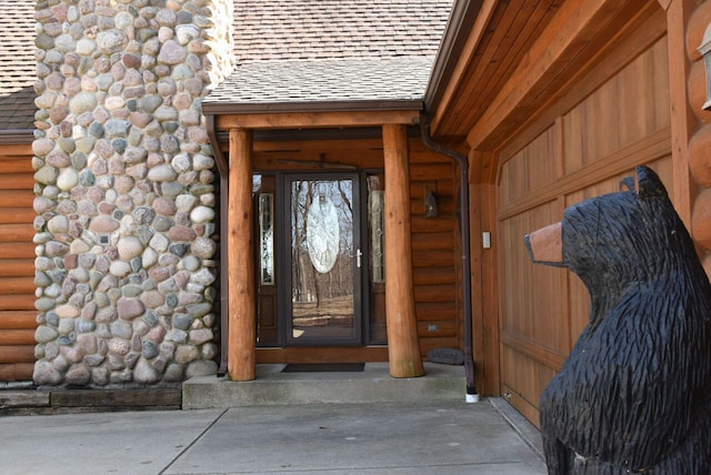 view of exterior entry featuring a shingled roof