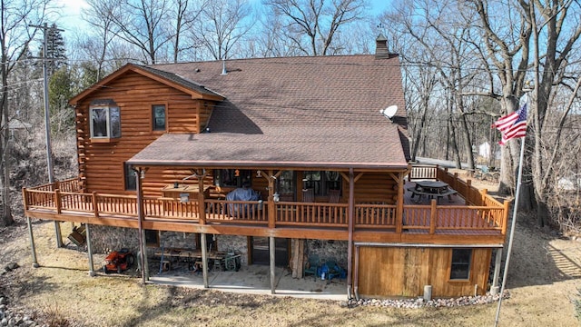 back of property with a wooden deck, log exterior, and a chimney