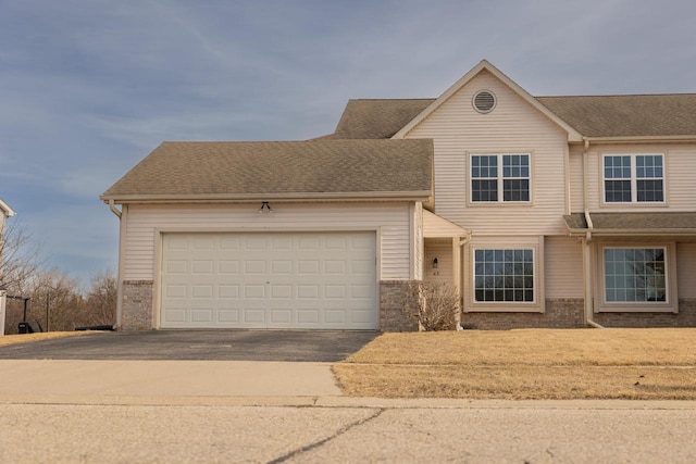 view of front of home featuring an attached garage, brick siding, driveway, and a shingled roof