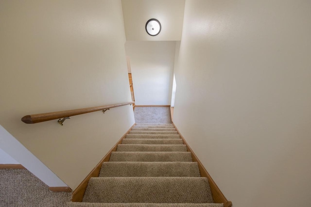 staircase featuring baseboards and carpet