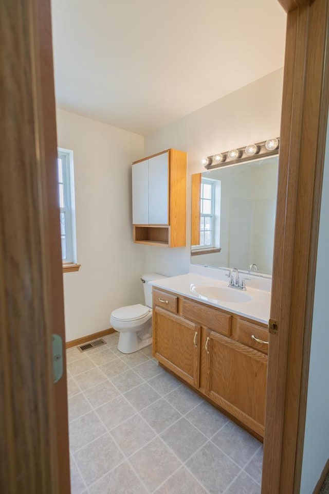 bathroom featuring visible vents, baseboards, toilet, tile patterned floors, and vanity