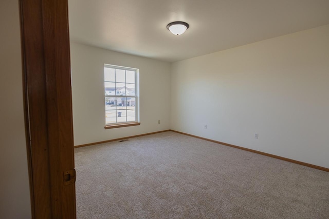 empty room featuring visible vents, light colored carpet, and baseboards