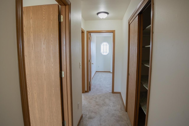 hall featuring light carpet and baseboards