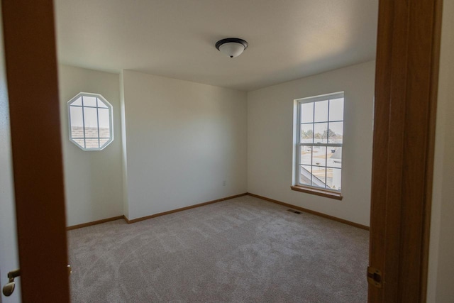 unfurnished room featuring light carpet, visible vents, and baseboards