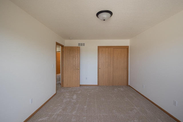 unfurnished bedroom with a closet, visible vents, baseboards, and carpet