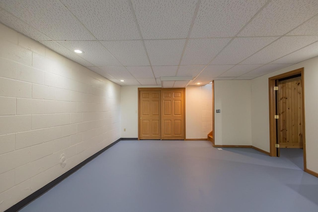 finished below grade area with recessed lighting, a drop ceiling, baseboards, and concrete block wall