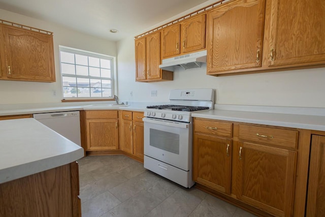 kitchen with under cabinet range hood, white appliances, light countertops, and a sink