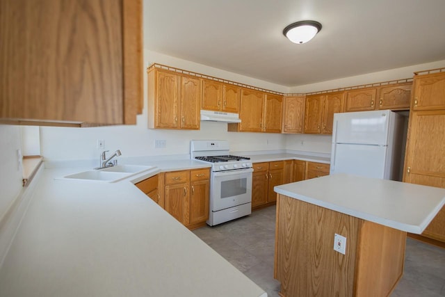 kitchen featuring a sink, white appliances, under cabinet range hood, and light countertops