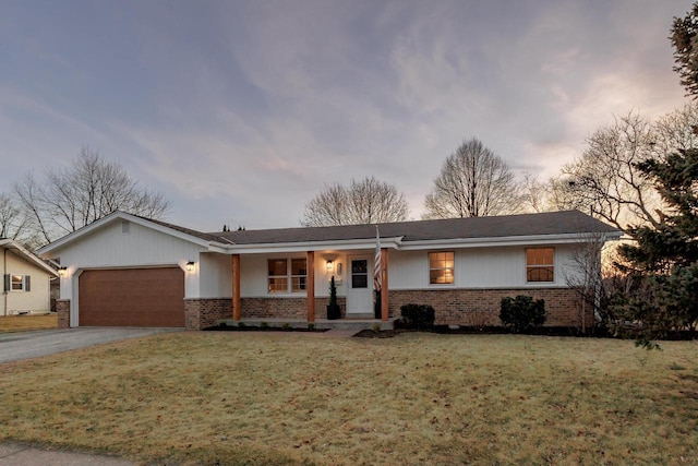 single story home with a front yard, brick siding, an attached garage, and driveway