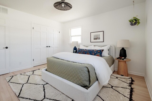 bedroom featuring a closet, visible vents, light wood-type flooring, and baseboards