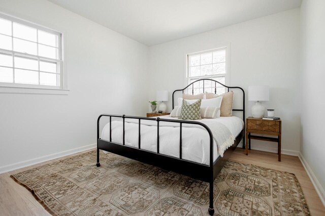 bedroom featuring multiple windows, baseboards, and wood finished floors