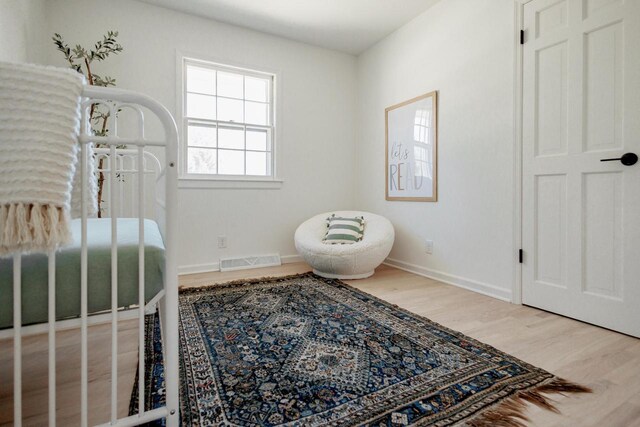 bedroom with wood finished floors, visible vents, and baseboards