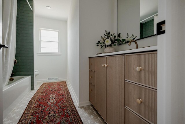 bathroom featuring visible vents, toilet, shower / tub combo, baseboards, and vanity