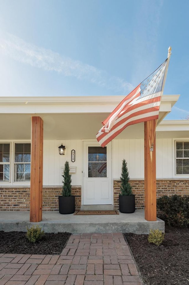 entrance to property with brick siding and a porch